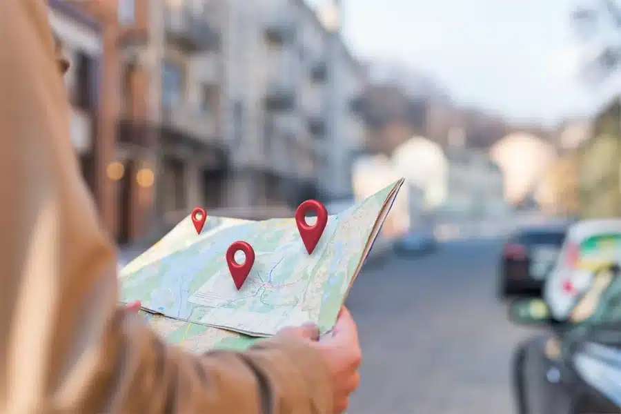 Man holding a map with digital location pins overlayed, representing local citations and geographic business visibility.